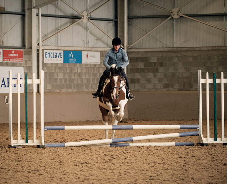 Trainer and Horse jumping over fence