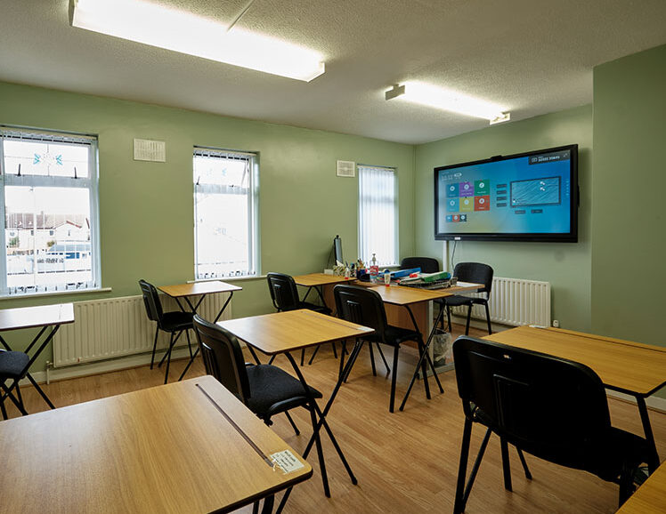 Classroom with table chairs and tv